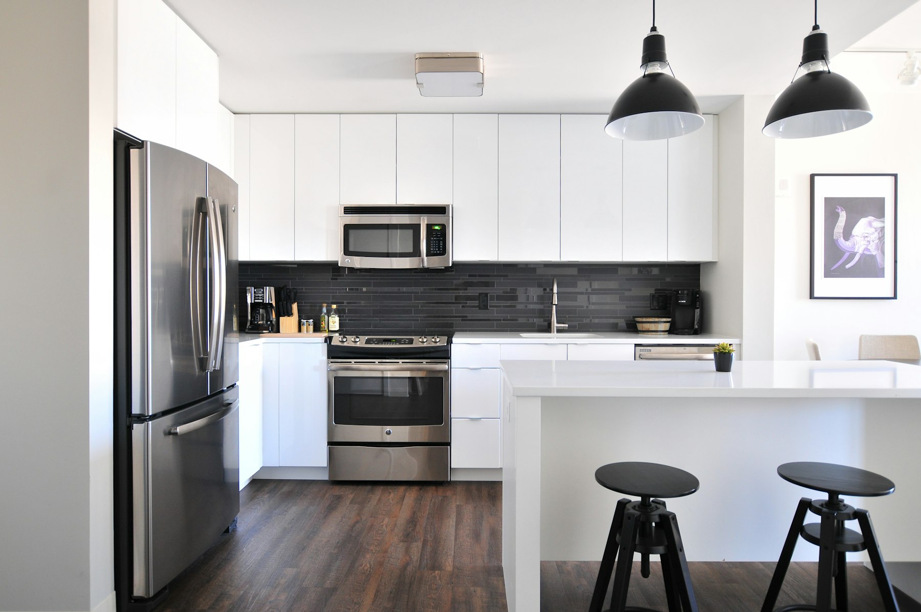 Open-plan kitchen with white cabinetry and stainless appliances