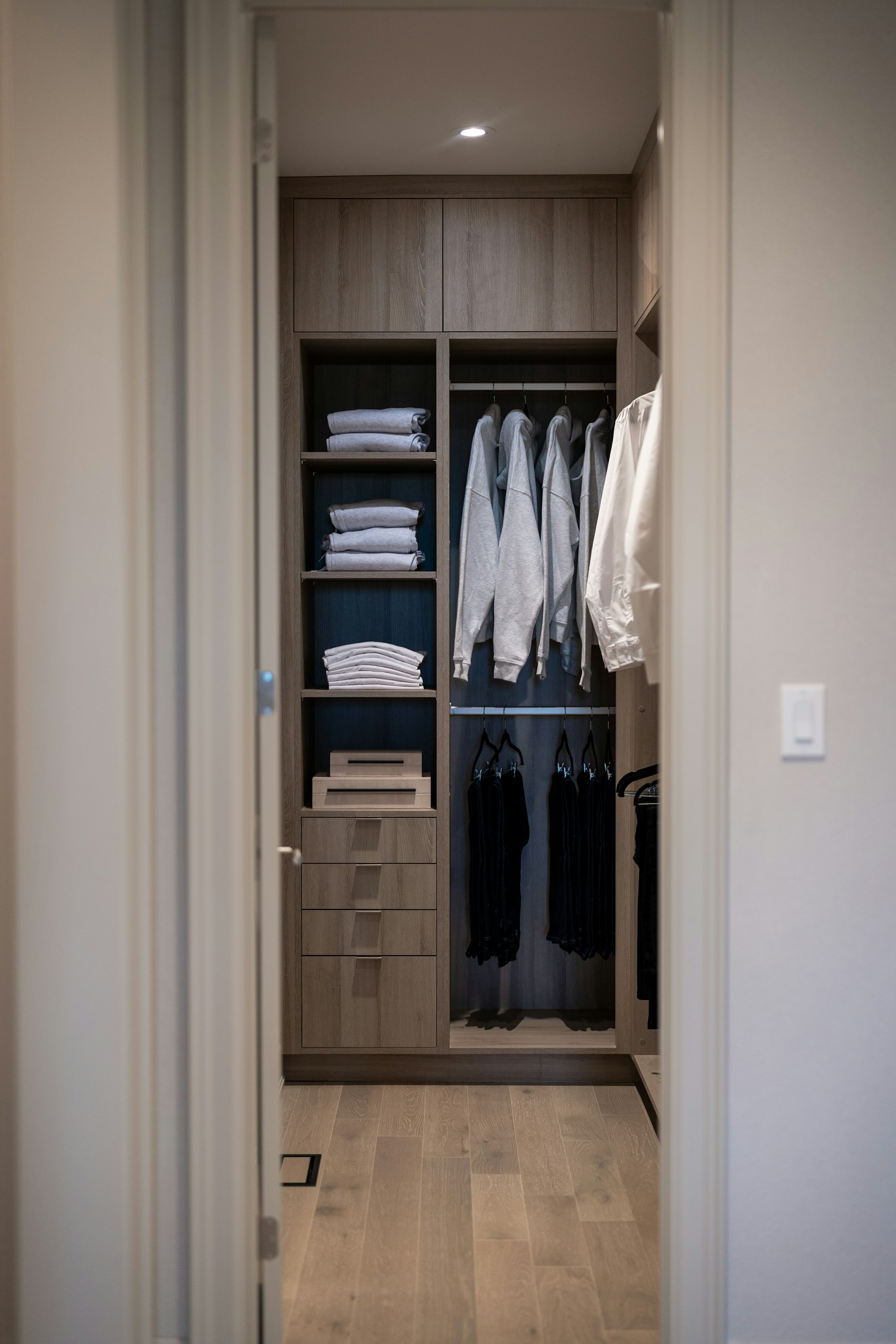 Organized walk-in closet with folded clothes and warm wood shelving